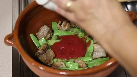 Adding tomato to a ceramic casserole. Rice preparation 库存影片 163706644