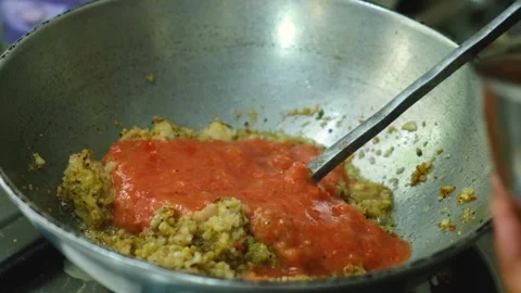 Adding tomato paste in frying masala for the vegetable Kofta curry an Indian Foo Stock Footage 248491007
