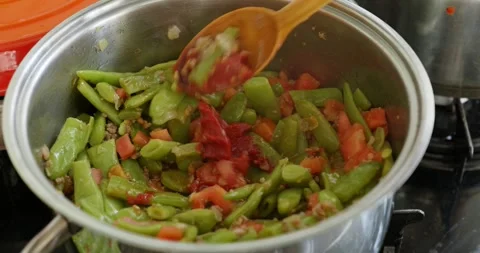 Adding Tomato Paste to Green Bean Stew with Wooden Spoon Stock Footage 317014366