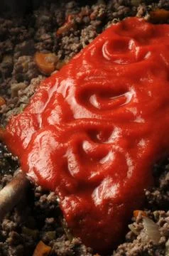 Adding tomato puree to minced meat Stock Photos