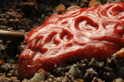 Adding tomato puree to minced meat Stock Photos