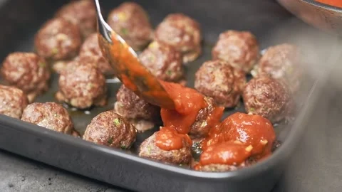 Adding tomato sauce in a baking tray with delicious small meatballs. Stock Footage 151046383