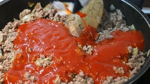 Adding tomato sauce to minced beef Stock Footage 219878646