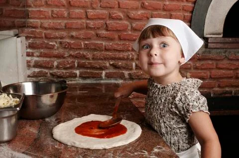 Adding tomato's sauce to pizza. Stock Photos