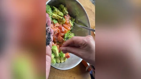 Adding topping to salmon and avocado poke bowl Stock Footage 333263140