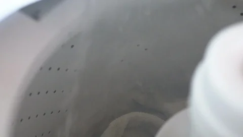 Adding towels to a top loading laundry machine filling up with hot water. Stock Footage 93241978