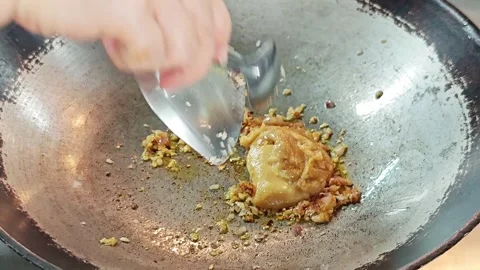Adding traditional palm sugar into a wok with chili and garlic close up. 스톡 동영상 339185124