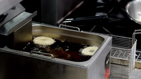 Adding uncooked donuts to deep fry in oil Stock-Footage 307339984