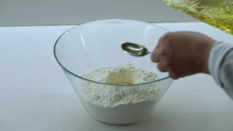 Adding vegetable oil to flour in bowl dough preparation close up Stock Footage 346093297