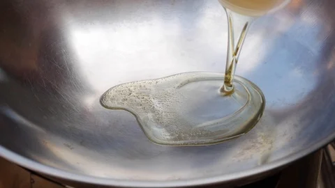Adding vegetable oil into a wok at the beginning of a cooking process. Step by Stock Footage 106809640