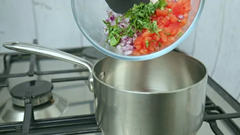 Adding vegetable sauce ingredients while frying in a pan on a gas stove in 4K. Stock Footage 142682755