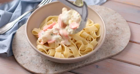 Adding vegetables and cream sauce to fettuccine pasta Video stock 103964457