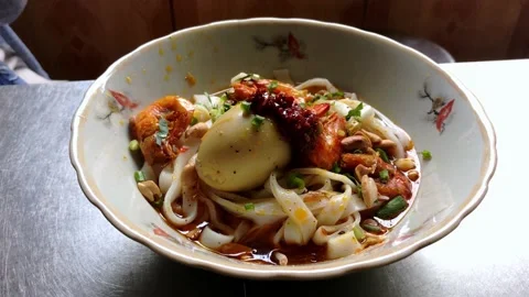 Adding vegetables and mixing a bowl of Mi Quang - Vietnamese rice noodle with Stock Footage 142343043
