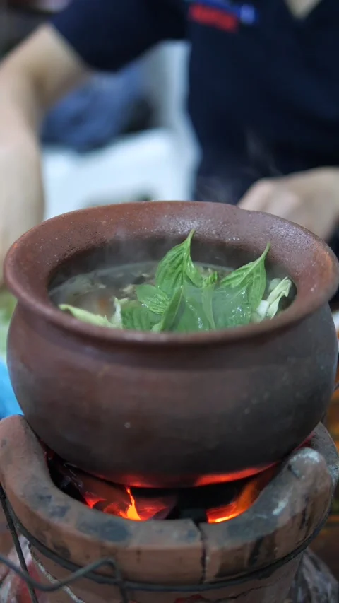 Adding Vegetables Into Boiling Shabu Hot Pot on Clay Stove Stock Footage 320768896