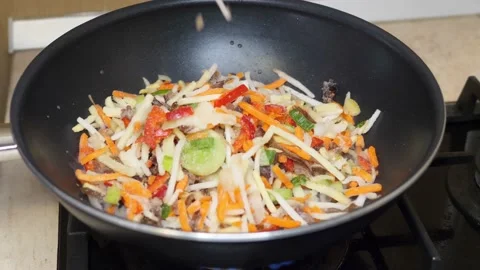 Adding vegetables into the wok on the stove Stock Footage 169769800