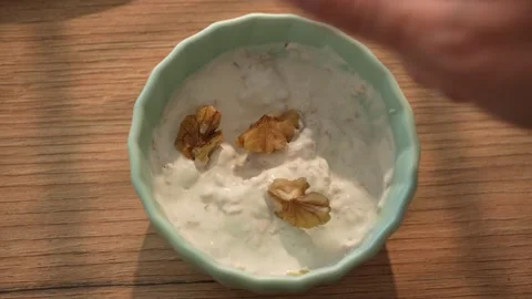 Adding walnut pieces into creamy yogurt mix Stock Footage 312708315