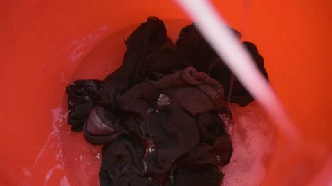 Adding water and detergent to the bucket with socks, creating lots of bubbles Stock Footage 329909874