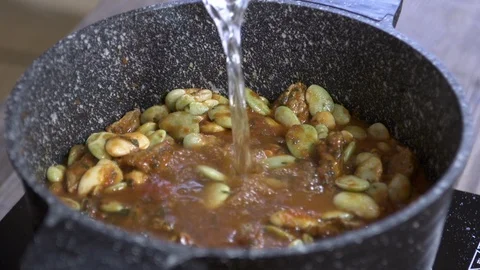 Adding water to bean stew cooked with beef, stiring bean stew, Lebanese cuisine Stock Footage 122449989