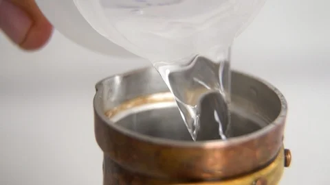 Adding water into copper Cezve Ibrik to make Turkish coffee closeup Stockbeeldmateriaal 123670580