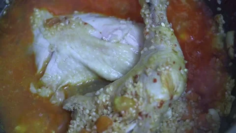 Adding water to fried chicken leg with fine rice in sunflower oil in a cauld Vídeos de archivo 220957688