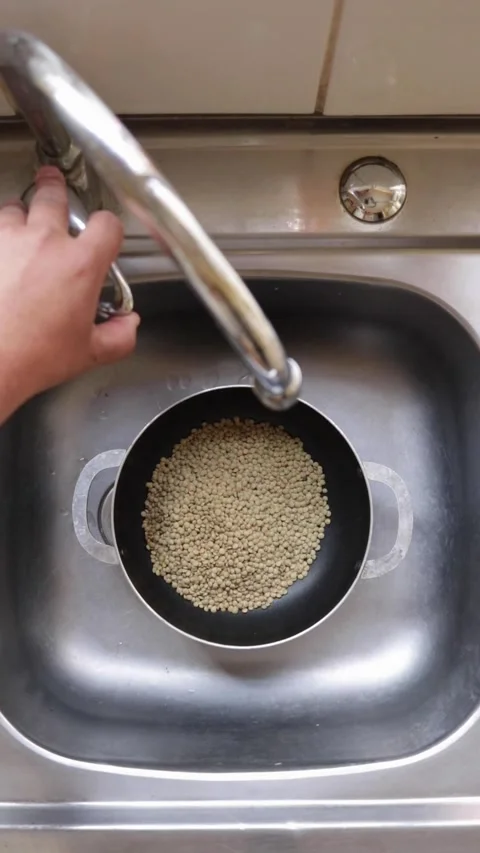 Adding water to a pot of lentils, seen from above Video stock 323241300