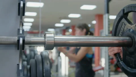 Adding Weight to barbell in gym in Slow-Motion Stock Footage 134340094