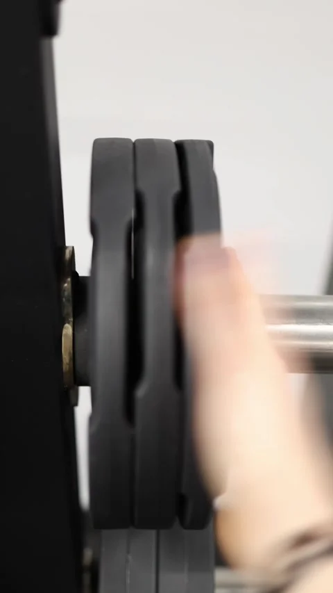Adding a weight plate to a barbell before training Stock Footage 337346311