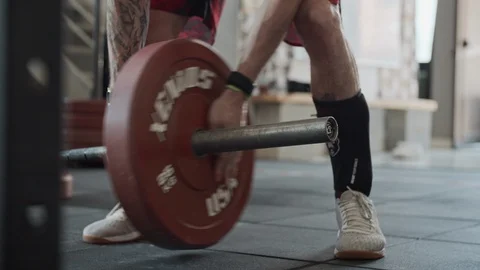 Adding weight plates to deadlift barbell in gym Видео 116881786