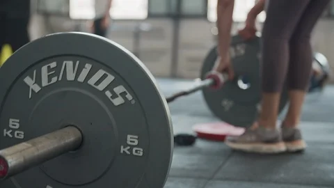 Adding weight plates to deadlift barbell in gym Stock Footage 116882193