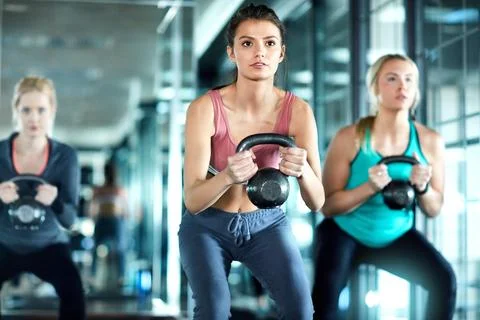 Adding weights can really change your game. three attractive young women working Stock Photos