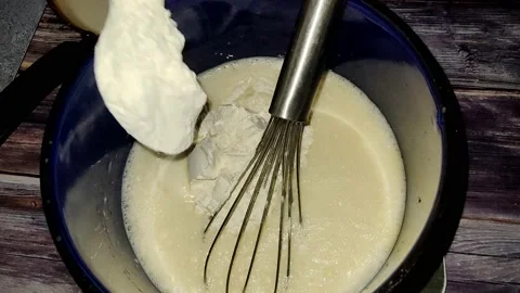Adding wheat flour to beaten eggs and milk in a blue saucepan Stock Footage 232945725