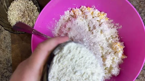 Adding wheat flour to the cottage cheese and raw eggs to make the cottage cheese Stock Footage 301324359