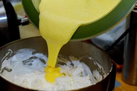 Adding whipped egg yolks in whipped egg white. Stock Photos