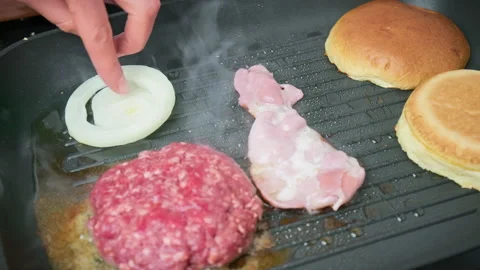 Adding white raw onion rings into a grilling pan for caramelizing in 4K. Stock Footage 153741206