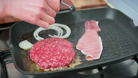 Adding white raw onion rings into a grilling pan for caramelizing in 4K. Stock Footage 153752998