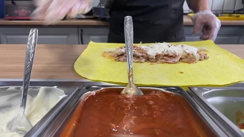 Adding white sauce and rolling shawarma on flatbread Stock Footage 318912178