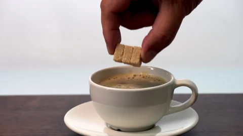 Adding whole 3 organic sugar cube in hot ceramic coffee cup on wooden table Stock Footage 317110500