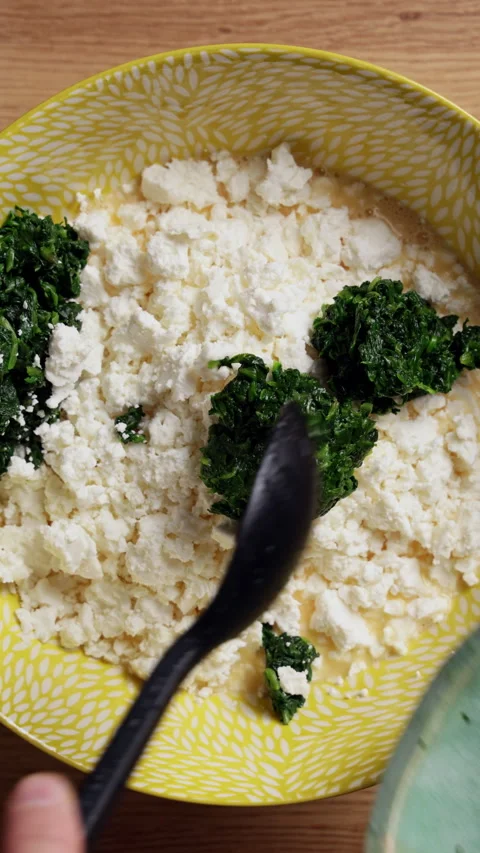 Adding Wilted Spinach To Feta Cheese Bowl Top View Vertical Stock Footage 337248605