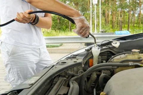 Adding windshield washer fluid at gasolin station by driver. Close-up of adding Foto stock