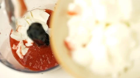 Adding yogurt in blender bowl filled with red liquid berries Stockbeeldmateriaal 124961275