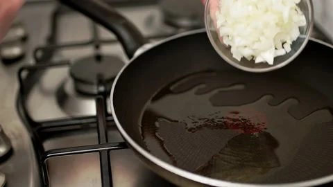 Adding/placing fine chopped onion in a preheated frying pan. Stock Footage 135312686