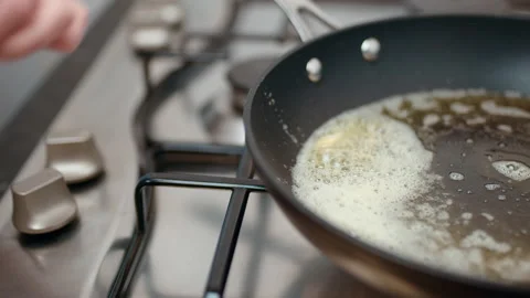 Adding/placing multiple prawns/shrimps in a frying pan with butter and oil in 4K Stock Footage 138286105