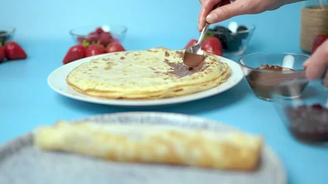 Adding/putting chocolate on french crepes in a serving plate. Video stock 133600366