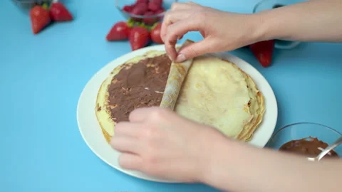 Adding/putting chocolate on french crepes in a serving plate. Stock Footage 133601726