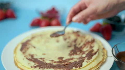 Adding/putting chocolate on french crepes in a serving plate. Video stock 133602058