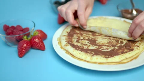 Adding/putting chocolate on french crepes in a serving plate. Stock Footage 133602815