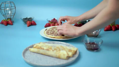 Adding/putting chocolate on french crepes in a serving plate. Video stock 133602903
