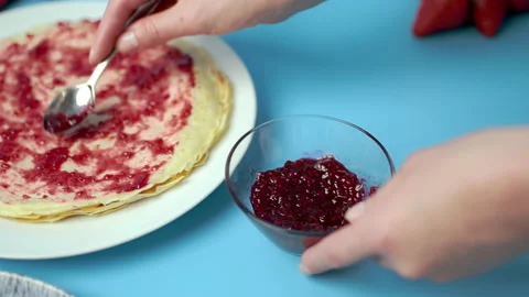 Adding/putting Roseberry jam on french crepes in a serving plate. Video stock 133603353