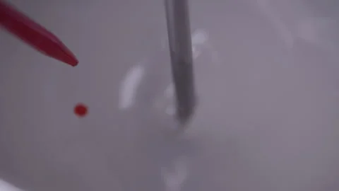 Addition of a drop of red dye with a pipette to a stirring mixture Stock Footage 340336108