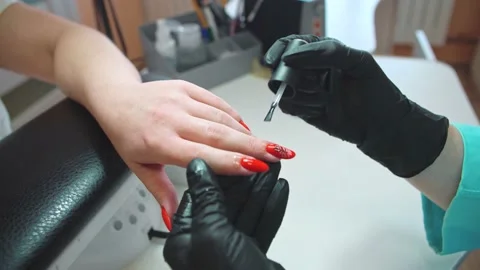 An additional cream varnish is applied to the hand with manicure with red nails, Stock Footage 152657078
